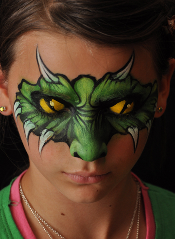 girl with a painted on face mask that covers just round her eyes and nose that looks like a lizzard with horns and when her eyes are closed they look like snake eyes